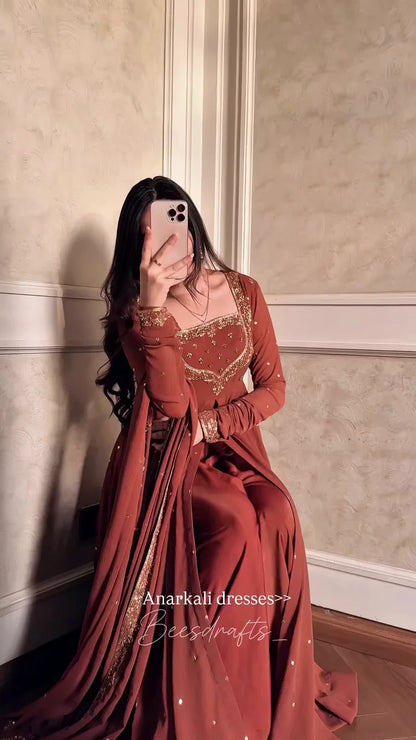 Cascading Layers of Terracotta Fabric Detailed with Intricate Yoke Embroidery and Scattered Motifs